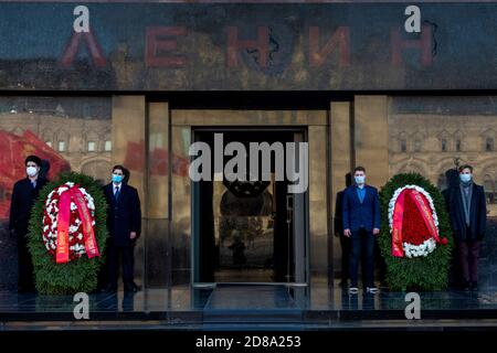 Moskau, Russland. 28. Oktober 2020 Anhänger der kommunistischen Partei mit Gesichtsmasken stehen in der Ehrenwache am Lenin-Mausoleum, mit roten Fahnen, die in ihrer Wand auf dem Roten Platz zum 102. Jahrestag des Komsomolens reflektiert werden, Oder die All-Union Leninist Young Communist League, die kommunistische Jugendorganisation der Sowjetzeit, in Moskau während der neuartigen Coronavirus COVID-19 Krankheit in Russland Stockfoto