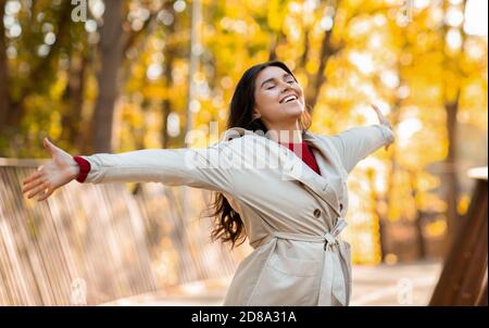 Fröhliche junge Dame in modischer Herbstkleidung fühlen sich frei und glücklich im Herbstpark, Panorama Stockfoto