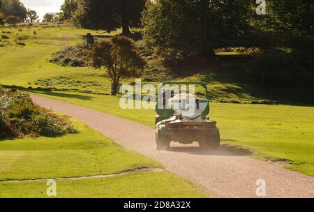 Ein Service-Fahrzeug auf einem Golfplatz, der Sand trägt, um die Bunker aufzufüllen, auf einer Straße durch den Golfplatz Stockfoto