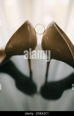 Hochzeitsschuhe und Ringe auf Glastisch Stockfoto