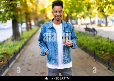 Lächelnder afrikanischer Mann mit Kaffee geht für eine Arbeit Stockfoto
