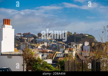 Ein Blick über die Dächer von Hastings Stadtzentrum auf die Ruinen der mittelalterlichen Burg auf dem West Hill. Stockfoto