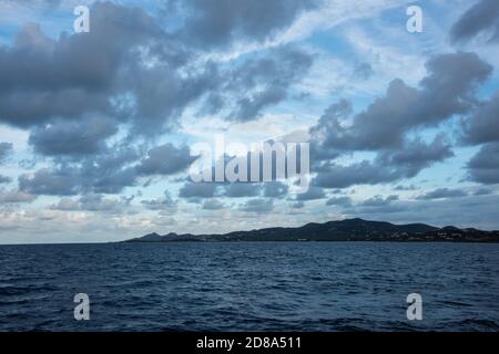 Blick vom Karibischen Meer in die hügelige Landschaft von St. Croix in der Abenddämmerung unter bewölktem Himmel. Stockfoto