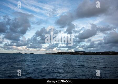 Blick vom Karibischen Meer in die hügelige Landschaft von St. Croix in der Abenddämmerung unter bewölktem Himmel. Stockfoto