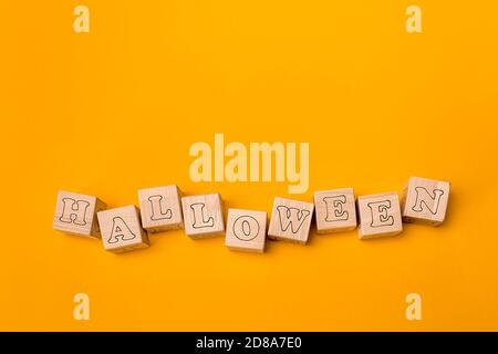 Hintergrunddesign im Stil von Halloween, Buchstaben auf Holzwürfeln. Durchgehend orangefarbener Hintergrund. Flach liegend. Stockfoto