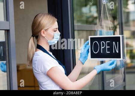 Seitenansicht der Kellnerin hängen und Blick auf Schild mit Offenes Wort an der Tür des Cafés Stockfoto