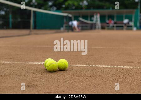 Drei Tennisbälle liegen zusammen auf einem roten Sandplatz. Stockfoto