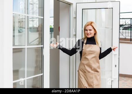 Halbe Länge Porträt der Kellnerin in Schürze gekleidet mit Kopieplatz für Markennamen Open Store Start Arbeit bereit, Besucher zu dienen, Frau Unternehmer Stockfoto