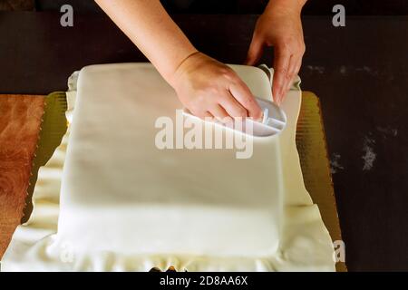 Frau Dekoration quadratischen Kuchen mit weißen Fondant. Technik der Herstellung Hochzeitstorte. Stockfoto