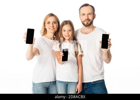 Lächelnde Familie in weißen T-Shirts mit Smartphones mit leeren Bildschirmen Isoliert auf Weiß Stockfoto