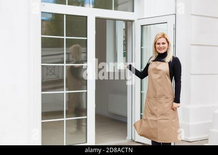 Halbe Länge Porträt der Kellnerin in Schürze gekleidet mit Kopieplatz für Markennamen Open Store Start Arbeit bereit, Besucher zu dienen, Frau Unternehmer Stockfoto