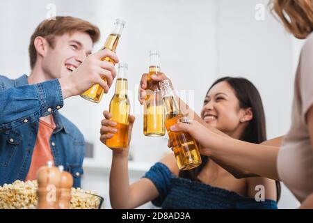 Selektiver Fokus von multiethnischen Freunden klirren Flaschen Bier während Party Stockfoto