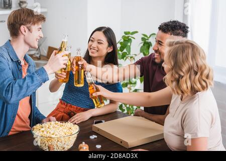 Aufgeregt multiethnischen Freunde klirren Flaschen Bier während der Party Stockfoto