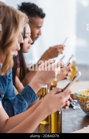 Selektiver Fokus von multiethnischen Freunden chatten auf Mobiltelefonen während Party Stockfoto