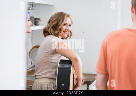 Selektiver Fokus der jungen Frau, die Gitarre spielt in der Nähe multikultureller Freunde Stockfoto