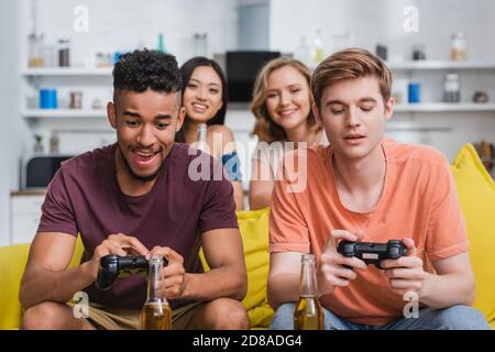 KIEW, UKRAINE - 28. JULI 2020: Multikulturelle Freunde spielen Videospiel während Party in der Küche Stockfoto