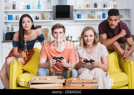 KIEW, UKRAINE - 28. JULI 2020: Multikulturelle Freunde spielen Videospiel in der Küche während der Party Stockfoto