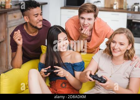 KIEW, UKRAINE - 28. JULI 2020: Aufgeregt multikulturelle Freunde spielen Videospiel während der Party Stockfoto