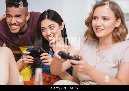 KIEW, UKRAINE - 28. JULI 2020: Selektiver Fokus der multiethnischen Freunde spielen Videospiel während der Party Stockfoto