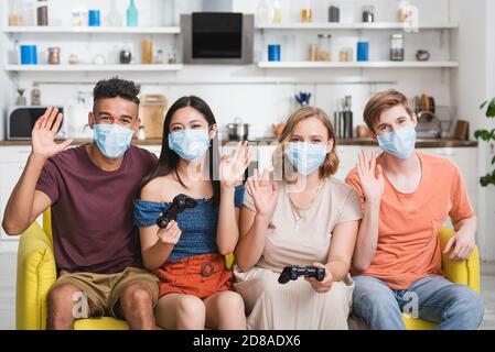 KIEW, UKRAINE - 28. JULI 2020: Multiethnische Freunde winken die Hände, während sie Joysticks halten Stockfoto