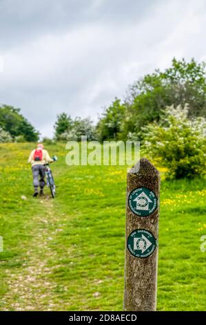 Ein Radfahrer schiebt sein Fahrrad auf Farthing Down über einen freizügigen Brückenweg. Teil des Londoner Grüngürtels. Stockfoto