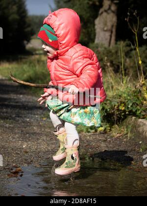 Happy Kleinkind springen in Pfützen, Großbritannien Stockfoto