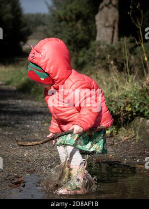 Happy Kleinkind springen in Pfützen, Großbritannien Stockfoto