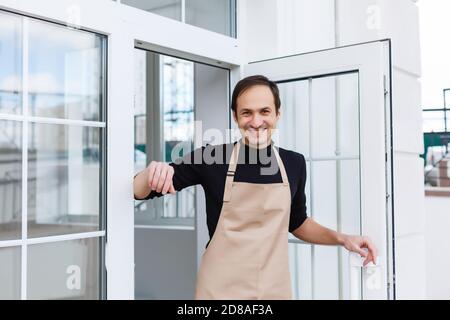 Porträt eines Kellners mit offenem Schild beim Kaffee Kaufen Stockfoto