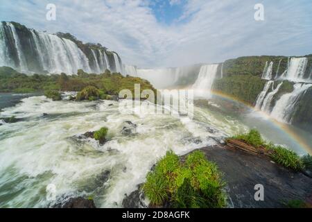 Malerischer Blick über die Iguazzu Wasserfälle in Brasilien. Die Wasserfälle in mehreren Kaskaden über eine Länge von 3 Kilometern. Im Vordergrund ein Regenbogen. Stockfoto