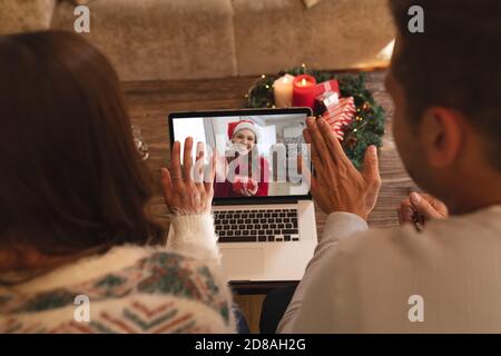 Rückansicht des Paares winken während mit einem Videocall mit Frau in santa Hut winken während halten gif Stockfoto