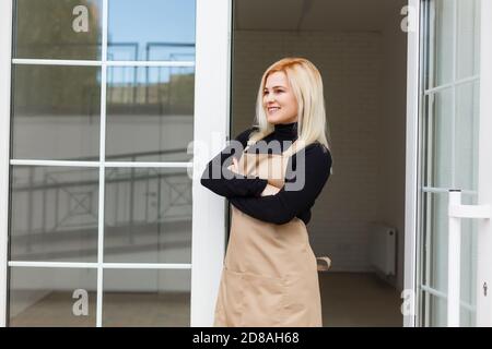 Halbe Länge Porträt der Kellnerin in Schürze gekleidet mit Kopieplatz für Markennamen Open Store Start Arbeit bereit, Besucher zu dienen, Frau Unternehmer Stockfoto