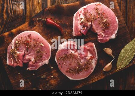 Raw Schweinelende Steaks mit verschiedenen Gewürzen Stockfoto