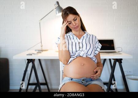 Schmerzen in der Schwangerschaft. Deprimiert schwangere Frau die Hand auf den Kopf Stockfoto