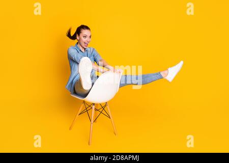 Volle Größe Profil Seite Foto von energetischen verrückten Mädchen sitzen Stuhl Stellen Sie sich vor, sie reiten Bergfahrer schnelle Geschwindigkeit tragen gut Schauen Sie Kleidung Schuhe isoliert Stockfoto
