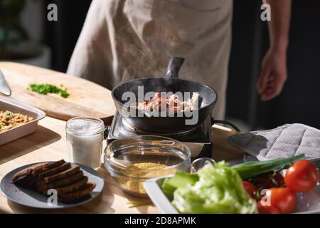 Nahaufnahme des in der Nähe des Kochers stehenden Kochers und Braten von Fleisch Mit Gemüse auf der Pfanne Stockfoto