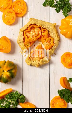 Torte mit gelben Tomaten, Paprika und Sesam, Galette mit Gemüse und Käse auf weißem Holzhintergrund, Draufsicht Stockfoto