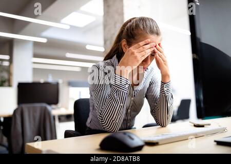 Überarbeitet und frustrierte junge Frau vor der Computer im Büro Stockfoto