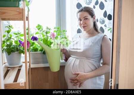 Frau Hausgärterin kümmert sich um ihre Blumen, stehen mit Gießkanne in der Hand Stockfoto