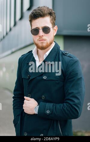 Vertikale Aufnahme eines jungen kaukasischen Mannes mit Sonnenbrille Stockfoto