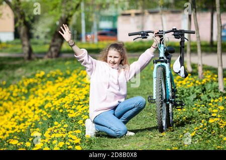 Teenager Mädchen grüßen oder jemanden anrufen, wenn neben ihrem Fahrrad sitzen, muss mit Fahrrad Panne helfen Stockfoto
