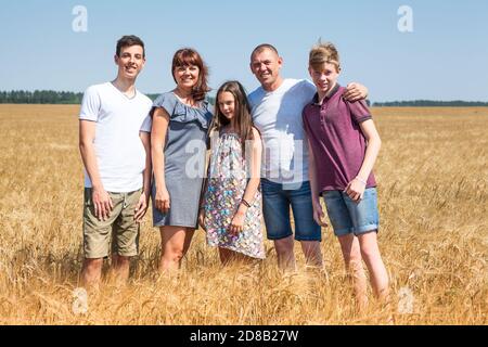 Getreidebauernfamilie mit Frau, zwei Söhnen im Teenageralter und einer Tochter im Teenageralter, langes Familienportrait auf gelben Weizenfeldern Stockfoto