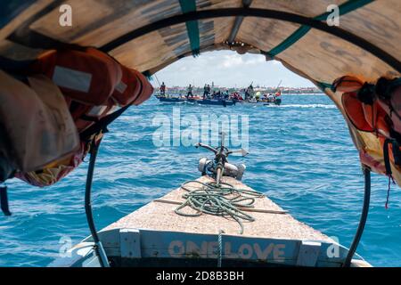 Bogenseite des traditionellen Sansibar Dhow Boot mit Anker und Seil mit einem anderen Boot in Front mit afrikanischen schwarzen Menschen Aufenthalt im Dhow Stockfoto