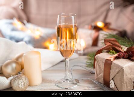 Ein Glas Champagner auf weihnachtlichem Hintergrund in gemütlicher Atmosphäre. Stockfoto