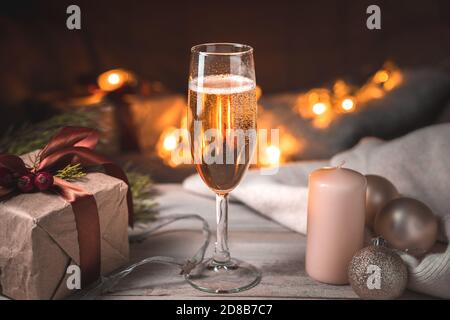 Abend Weihnachten Hintergrund mit einem vollen Glas Champagner auf dem Hintergrund einer brennenden Girlande. Stockfoto