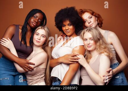 Junge hübsche kaukasische, afro, skandinavische Frau posiert fröhlich zusammen auf braunem Hintergrund, Lifestyle diverse Nationalität Menschen Konzept Stockfoto