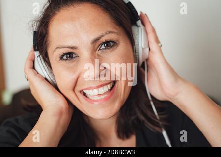 Nahaufnahme Porträt der glücklichen und schönen Frau trägt Kopfhörer Während Sie Ihre Musik zu Hause genießen Stockfoto