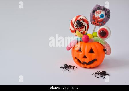 Kürbisse mit verschiedenen Süßigkeiten auf einem violetten Hintergrund mit einer Kopie des Raumes. Herbsturlaub. Postkarte. Banner für Halloween Stockfoto