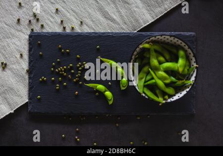 Edamame Bohnen in einer Schüssel. Sojabohnen und Mung auf einem Schieferbrett. Gesunde Hülsenfrüchte mit Proteinen. Stockfoto