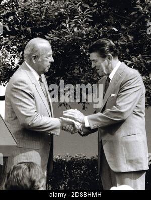 US-Außenminister George P. Shultz schüttelt sich die Hände mit US-Präsident Ronald Reagan, nachdem er eine kurze Erklärung abgegeben hat, nachdem er am 16. Juli 1982 im Rosengarten des Weißen Hauses in Washington, DC, den Amtseid abgelegt hat. Quelle: Howard L. Sachs/CNP weltweit Stockfoto