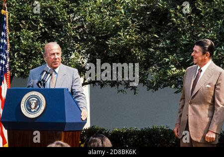 US-Außenminister George P. Shultz gibt eine kurze Erklärung ab, nachdem er den Amtseid während einer Zeremonie im Rosengarten des Weißen Hauses in Washington, DC am 16. Juli 1982 abgelegt hat. US-Präsident Ronald Reagan schaut von rechts.Quelle: Howard L. Sachs/CNP weltweit Stockfoto